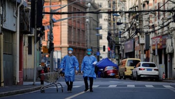 FILE PHOTO: Workers in protective suits walk with a cart along a street during lockdown, amid the coronavirus disease (COVID-19) pandemic, in Shanghai, China, May 25, 2022. REUTERS/Aly Song/File Photo