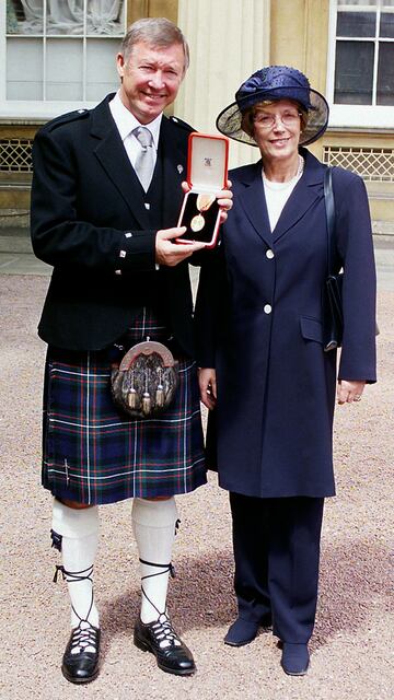 Ferguson posa con su mujer Cathy después de la ceremonia en la que fue nombrado Sir en el Buckingham Palace en 1999.