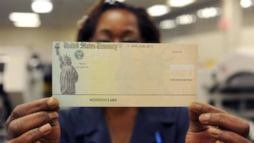 Persona sosteniendo un cheque de estímulo vía Getty Images, 2020.