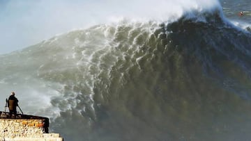 La ola gigante de Nazaré (Portugal) a punto de romper con una persona mirándoselo desde el faro de Praia do Norte.