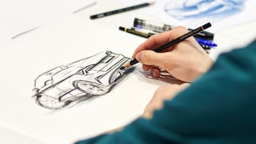 Un diseñador que dibuja un auto en papel