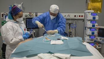 MADRID, SPAIN - FEBRUARY 24: Doctor Borja Ruíz (R) and other health care workers carry out a procedure on the vein of a Covid-19 patient at the Intensive Care Unit in Nurse Isabel Zendal Emergency Hospital on February 24, 2021 in Madrid, Spain. The City of Madrid community built the 80,000 m2 hospital, which can accommodate up to 1,000 patients at a time, in just 100 days after the first wave of the Covid-19 pandemic. (Photo by Pablo Blazquez Dominguez/Getty Images)