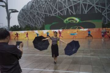 Una mujer posa ante El Nido, el estadio nacional de Pekín, que acoge los Campeonatos del Mundo de atletismo 2015.