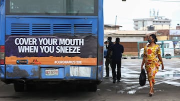 A woman wearing a protective face mask walks past a public bus on the first day of the easing of lockdown measures during the outbreak of the coronavirus disease (COVID-19) in Lagos, Nigeria May 4, 2020. REUTERS/Temilade Adelaja