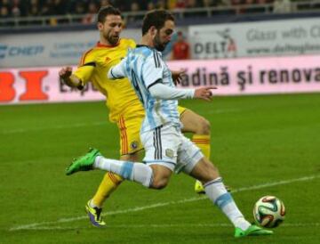 Gonzalo Higuaín de Argentina compite por el balón contra Razvan Rat (L) de Rumania durante el partido de fútbol amistoso internacional Rumania - Argentina en Bucarest.