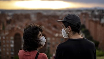 Dos personas con mascarilla divisan Madrid desde el Parque del Cerro del T&iacute;o P&iacute;o, en Vallecas.