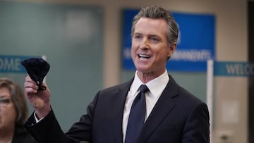 Gov. Gavin Newsom holds a face mask while speaking at a news conference in Oakland.