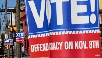 PHILADELPHIA, PA - NOVEMBER 07: A man walks between signs that state "VOTE DEFEND DEMOCRACY on NOV. 8th" affixed to telephone poles the day before the midterm general election on November 7, 2022 in Philadelphia, Pennsylvania. In closely watched Pennsylvania election races, Democratic candidate for U.S. Senator John Fetterman faces Republican nominee Dr. Mehmet Oz and Democratic candidate for Governor Josh Shapiro faces Republican Doug Mastriano on November 8. (Photo by Mark Makela/Getty Images)