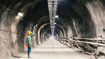 Professional underground workerpointing downward in a tunnel/mine.