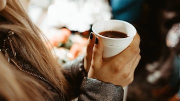 Una mujer se calienta con una taza de vino caliente.