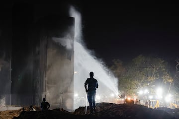 Un chorro de agua se roca sobre un edificio mientras el personal de seguridad se encuentra en el lugar del accidente despus de que un avin de Air India, con destino al aeropuerto Gatwick de Londres, se estrellara durante el despegue de un aeropuerto en Ahmedabad, India.