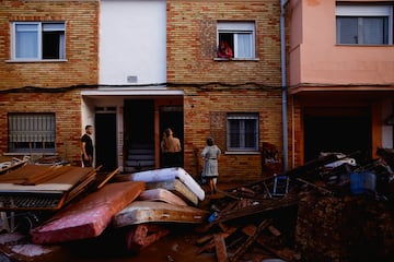 Los residentes se encuentran fuera de sus casas junto a sus pertenencias dañadas después de las inundaciones en Utiel, España.