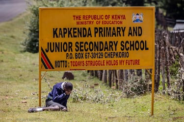 Un estudiante llora junto a la carretera después de ver el automóvil que transportaba el ataúd del difunto corredor de maratón.