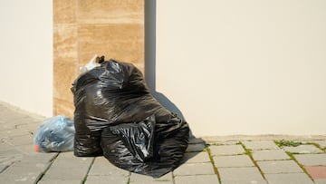 pile of garbage in black plastic garbage bags on the sidewalk by the road in a big city, space for text, garbage from pollution. Waste recycling, recycling and city ecology