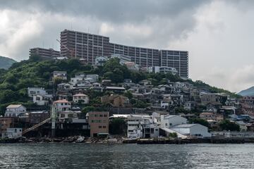 La isla Hashima, ahora un destino turstico, comnmente llamada Gunkanjima (Isla del Acorazado) debido a su forma, era conocida por sus minas de carbn submarinas que funcionaron durante la industrializacin de Japn. Con el paso del tiempo, se construyeron complejos de apartamentos apretados para los mineros y los trabajadores, lo que provoc su rcord de densidad. Pero la gente se fue tan rpido como lleg cuando el carbn se agot. La isla alcanz una poblacin mxima de 5.259 habitantes en 1959, pero en 1974, cuando las reservas de carbn estaban a punto de agotarse, la mina se cerr y todos los residentes se marcharon, dejando la isla abandonada durante tres dcadas. El inters resurgi en la dcada de 2000 debido a sus ruinas histricas intactas y se abri a los turistas en 2009. Aqu se filmaron escenas de la pelcula de James Bond de 2012 "Skyfall" y la isla obtuvo el estatus de Patrimonio Mundial de la UNESCO en 2015. Aunque principalmente es un smbolo de la rpida industrializacin de Japn, la isla tambin ha llegado a servir como recordatorio de su historia como sitio de trabajo forzado para poblacin coreana y china antes y durante la Segunda Guerra Mundial.  Ahora es una ciudad fantasma de roca y hormign en medio del ocano.