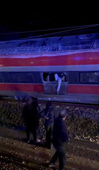 Una persona sale de un tren descarrilado mientras los servicios de emergencias buscan entre los restos después de que dos trenes de alta velocidad descarrilaran en Adamuz, cerca de Córdoba, España.