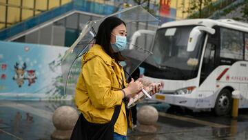A woman holds eggs as she waits to cross a street on a rainy day in Beijing on September 23, 2020. (Photo by WANG ZHAO / AFP)