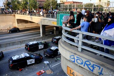 Un manifestante lanza piedras desde un paso elevado a vehículos policiales en una carretera, durante una protesta contra las redadas federales de inmigración, en el centro de Los Ángeles.
