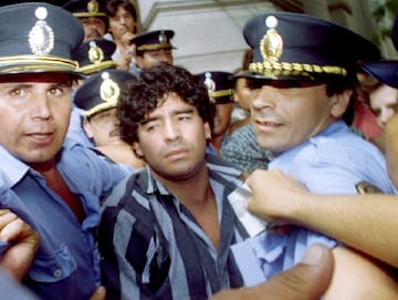 Diego Maradona escoltado por la policía cuando sale de un juzgado después de responder a los cargos por disparos a periodistas fuera de su casa de campo dos meses antes, en la ciudad de Mercedes, a 100 kilómetros de Buenos Aires, el 15 de marzo. 1994.