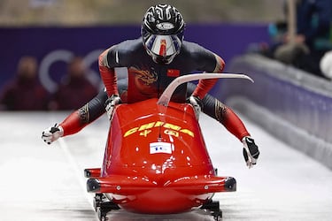 Los chinos Sun Kaizhi y An Tai conforman una imagen que engaña al cerebro ya que da la sensación de que es un solo competidor subiéndose, cuando en realidad es el espectacular baile de poner en acción el veloz vehículo durante la competición de bobsleigh masculino por parejas, disputado en el centro de deslizamiento de Cortina de los Juegos Olímpicos.