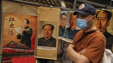 A man wearing a protective face mask walks past a a stall selling portraits of former Chinese leader Mao Zedong at Panjiayuan Antique market in Beijing, China, 23 May 2020. 