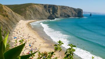 Esta playa nace en una bonita ensenada en forma de concha, resguardada del fr¨ªo viento y las olas del norte, junto a un n¨²cleo pesquero. El arenal es extenso ¡ªm¨¢s de 700 metros¡ª, pero estrecho, y se encuentra bordeado de imponentes acantilados negros tallados en pizarra. Mirando hacia el sur, sobresale en el paisaje una roca oscura y estrecha que emerge del mar. Se trata de Pedra da Agulha, todo un icono de la costa vicentina.