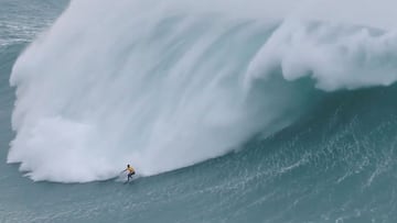 La ola gigante de Nazaré (Portugal) rompiendo sobre un surfista con licra amarilla.