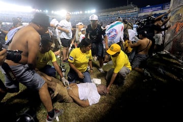 Personal de atención médica atiende a un hombre herido que yacía en la cancha tras la estampida.