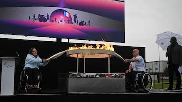 Britain's Helene Raynsford and Gregor Ewan light torches from the cauldron during the Paralympic torch-lighting ceremony at Stoke Mandeville in Aylesbury, central England on August 24, 2024. Four days before the Paris Paralympic Games begins, the Paralympic flame was lit on Saturday next to the English hospital where the idea for the competition was born. The Paralympic movement dates back to 1948, when German neurologist Ludwig Guttmann organised sporting events for injured veterans at Stoke Mandeville Hospital, northwest of London. The flame will pass through the Channel Tunnel on Sunday, with 24 British torchbearers taking it halfway, before handing it over to 24 French torchbearers, who will take it to Calais. (Photo by JUSTIN TALLIS / AFP)