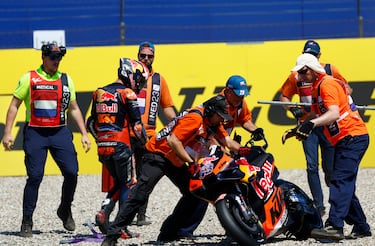 Comisarios de carrera levantan la KTM de Jack Miller tras la caída del piloto australiano en la segunda vuelta.