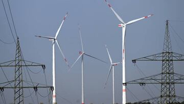 29 August 2022, North Rhine-Westphalia, Neurath: Wind turbines for power generation stand behind electricity pylons. Consumers and businesses in Germany are worried about sharp increases in energy prices. Photo: Federico Gambarini/dpa (Photo by Federico Gambarini/picture alliance via Getty Images)