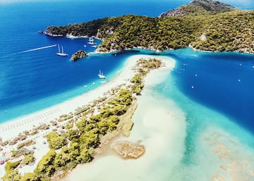 La Playa de Oludeniz es un litoral largo de guijarros con vistas al mar Mediterráneo y al Egeo. Oludeniz es un pequeño barrio y balneario en el distrito de Fethiye de la provincia de Mugla, en la Costa Turquesa del sudoeste de Turquía. Es también conocida como como Blue Lagoon.