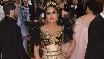 Salma Hayek en Met Gala 2019, portando un vestido dorado con toques excéntricos en color negro.