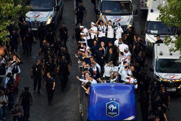 France's defender Raphael Varane (C) hold the trophy as he celebrates with teammates on the roof of a bus as they arrive at the Champs-Elysees avenue in Paris, on July 16, 2018 after winning the Russia 2018 World Cup final football match. / AFP PHOTO / Be