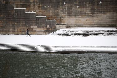 Una persona corre por las orillas nevadas del río Sena en París mientras el clima invernal con nieve y temperaturas frías azota una parte del país, Francia.
