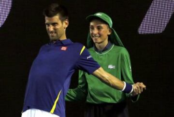 Novak Djokovic hace estiramientos con la ayuda de un recogepelotas en el partido ante Kei Nishikori del Open de Australia.