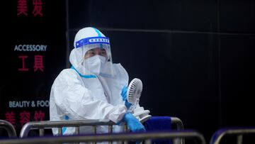 A medical worker in a protective suit uses a fan at a nucleic acid testing station, following the coronavirus disease (COVID-19) outbreak, amid a heatwave warning in Shanghai, China, August 23, 2022. REUTERS/Aly Song