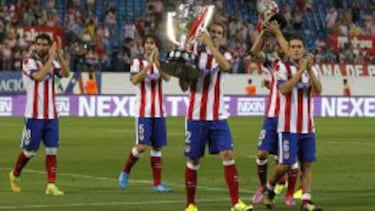 Los jugadores del Atlético ofrecen los trofeos de Liga y Supercopa a su afición.