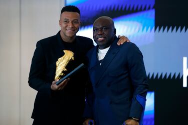 El delantero francés del Real Madrid Kylian Mbappé posa junto a su padre, Wilfried Mbappé, tras recibir este viernes la Bota de Oro en un acto celebrado en el palco del Santiago Bernabéu.