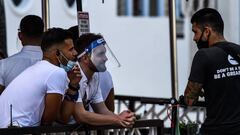 Un camarero se cubre la cara con un escudo mientras conversaba con otro hombre en un restaurante en Ocean Drive en Miami Beach, Florida, el 14 de julio de 2020, en medio de la pandemia de coronavirus.