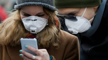 FILE PHOTO: People wearing protective face masks use a smartphone on a street amid coronavirus (COVID-19) concerns in Kiev, Ukraine March 17, 2020.  REUTERS/Valentyn Ogirenko/File Photo