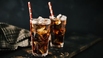 Close up glass of refreshing cola with ice on table.