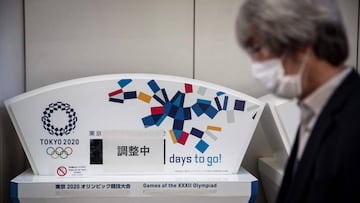 Un hombre con mascarilla pasa delante de un contador de d&iacute;as para los Juegos Ol&iacute;mpicos de Tokio 2020.