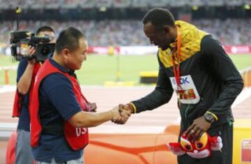 El cámara de televisión que se llevó en su 'Segway' por delante a Usain Bolt en la vuelta de honor de la final de 200m y el propio jamaicano se saludan tras el incidente.