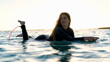 La surfista Andrea Buch estirada sobre su tabla de surf con el sol al fondo en Fuerteventura (Islas Canarias).