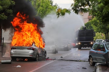 A police water cannon tries to extinguish the fire from a burning police car, during clashes between Kosovo police and ethnic Serb protesters, who tried to prevent a newly-elected ethnic Albanian mayor from entering his office, in the town of Zvecan, Kosovo, May 26, 2023. REUTERS/Miodrag Draskic