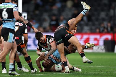 Ronaldo Mulitalo, de los Cronulla-Sutherland Sharks, es atropellado por dos jugadores de los Wests Tigers
mientras defiende la posesión durante la 19ª jornada de la NRL, la competición más importante de rugby en Australia. Su cuerpo es totalmente abordado por los rivales mientras consigue mantener el oval en su mano.