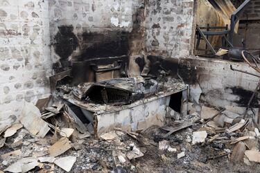 Los escombros cubren el suelo de los restos de una casa quemada. 