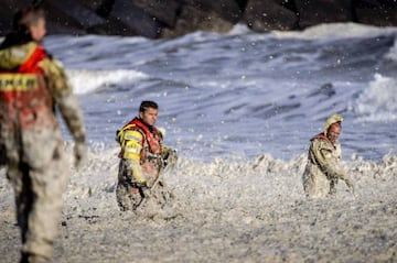 Varios trabajadores del KNRM buscan entre la espuma que se generó en Scheveningen durant el temporal del lunes.