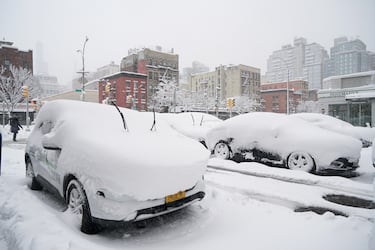 Autos cargados de nieve estacionados en la calle lateral entre la calle 20 Este y la Primera Avenida.